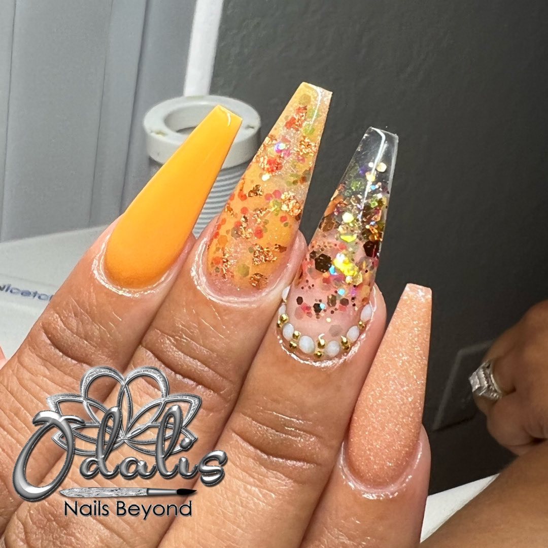 Orange coffin nails with all of these gemstones will look amazing for the summer.