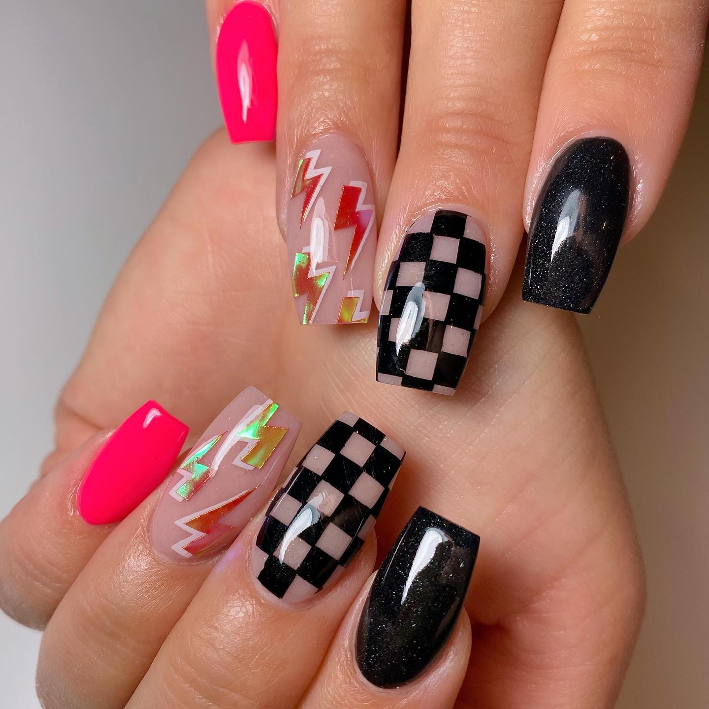 A mixture of bright lightning bolts, neon pink, dama and glittered black nails. Wow. It's for those who want to catch everyone's attention.