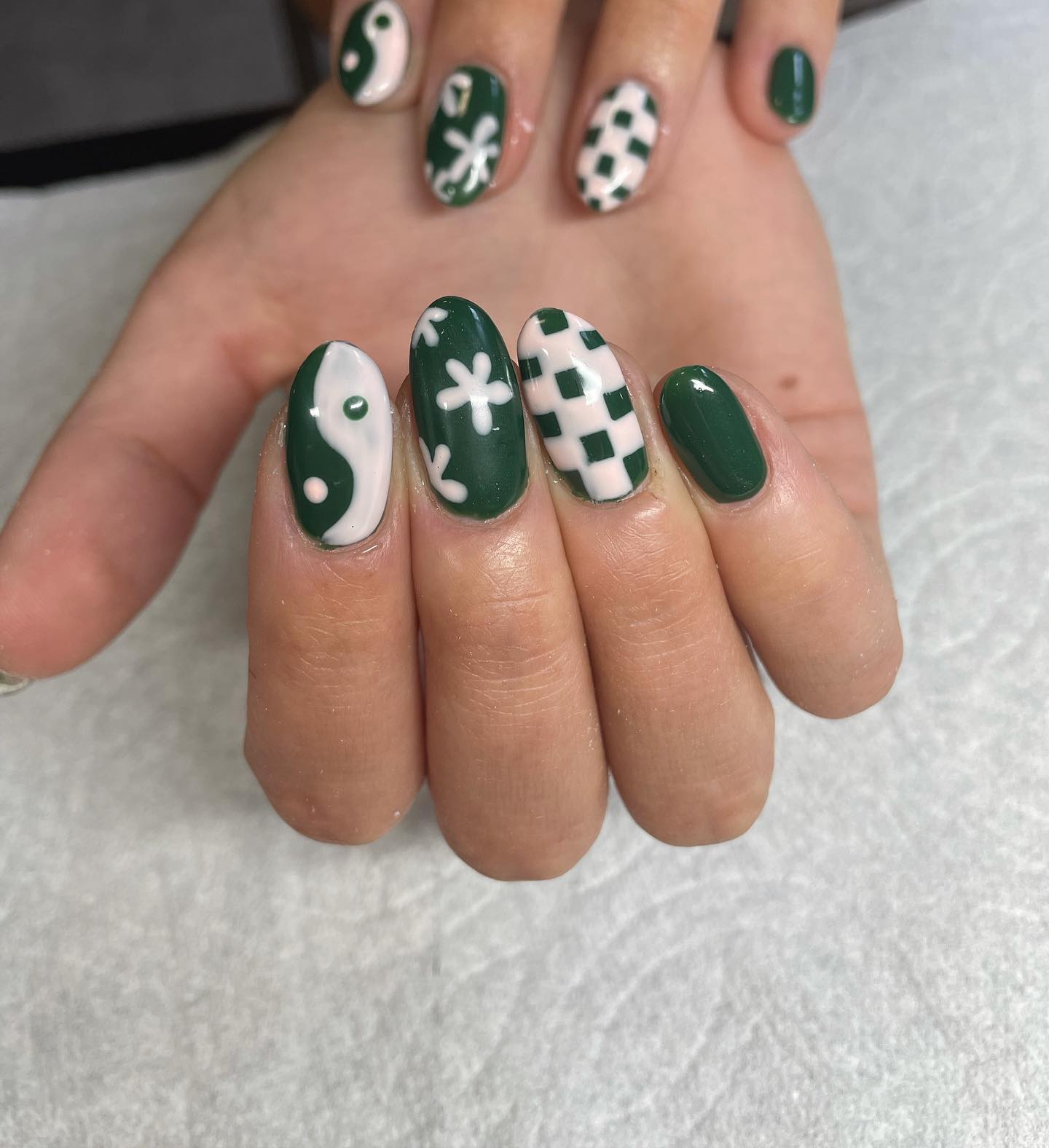 Who can say no to a mixture of dama, flowers and ying yang nails? You will definitely have a different style with this. White nail polish suits well with dark green, too.