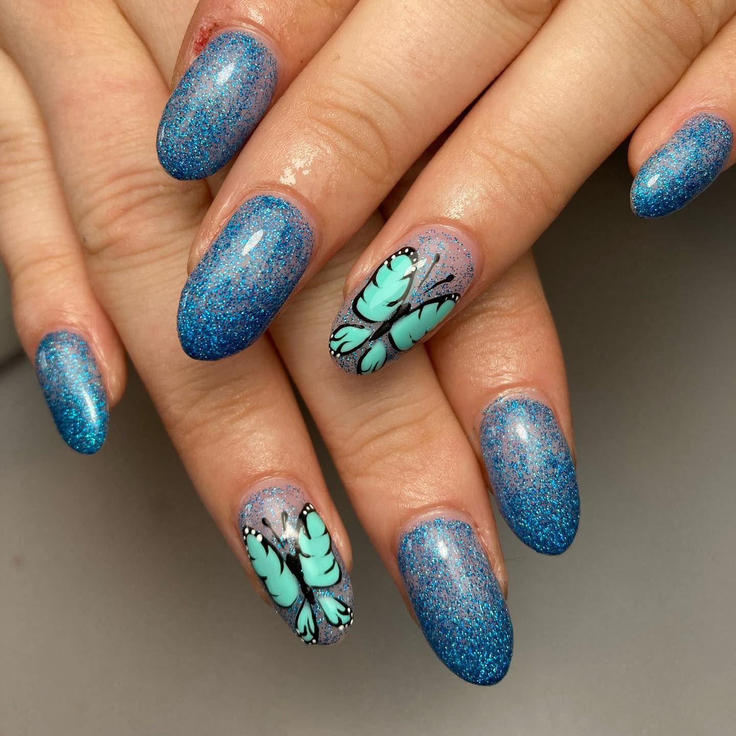 It is amazing to see how well blue and green colors go with together. On top of glittered blue nails, it is a great idea to create green butterflies.
