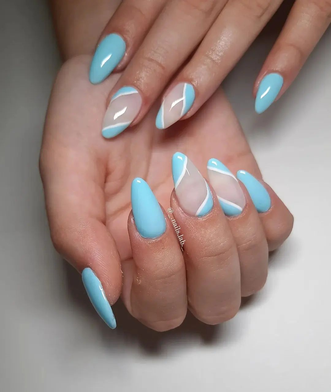 As accent nails, you can use a transparent base and draw some random lines of white and light blue colors. Long almond nails go with this nail design, too.