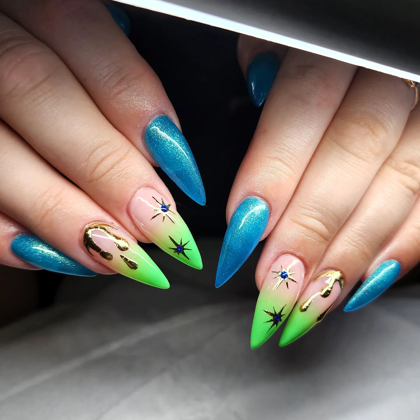 Shiny blue and green ombre stiletto nails look fabulous. If you want to add more to them, some gold stars and drip drops are the things that you should consider.