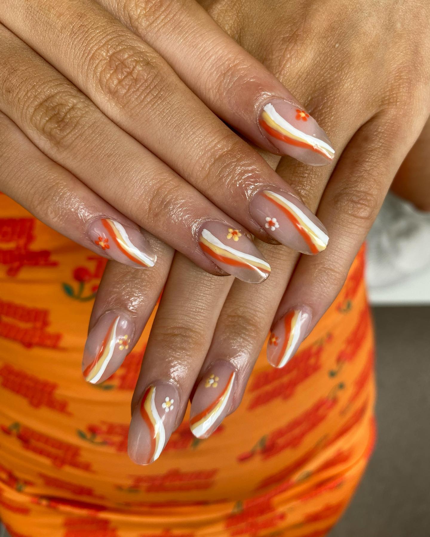 A transparent base with thick orange swirls will look fabulous on you! Try this out and forget to add some daisies on top of your nails.