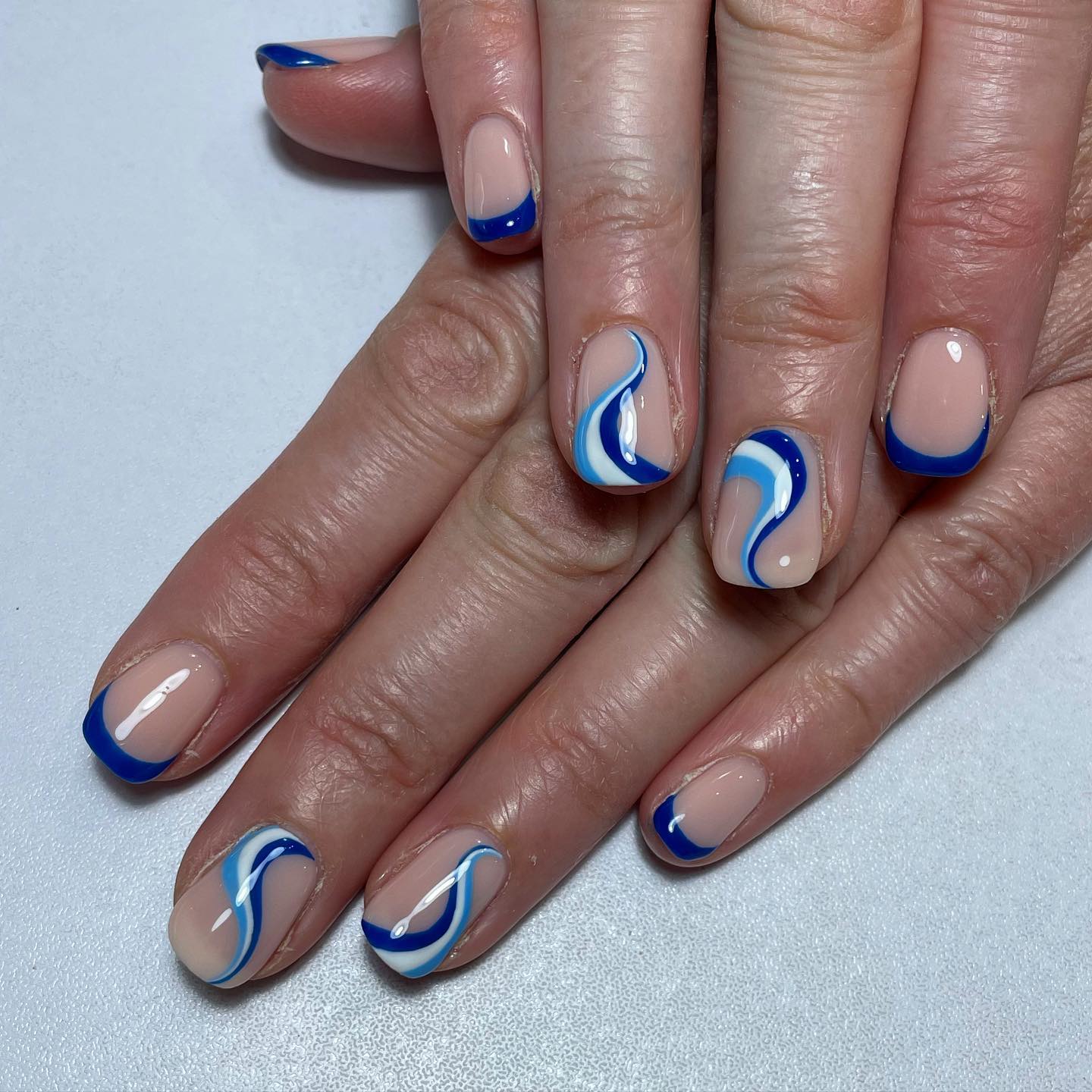 Combinados con puntas francesas de color azul oscuro, los remolinos azules y blancos le recuerdan a alguien las hermosas olas de un océano.  Anímate si te gusta el color azul y los remolinos.