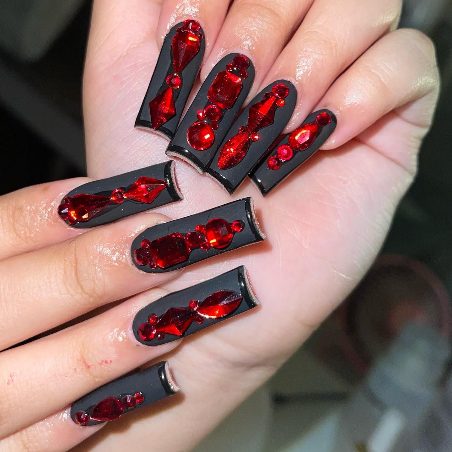 Long black acrylic nails are taken to a whole different level with red color. This time it is not the red nail polish but red stones that offer a great look for your black nails. Let's get them to stand out.