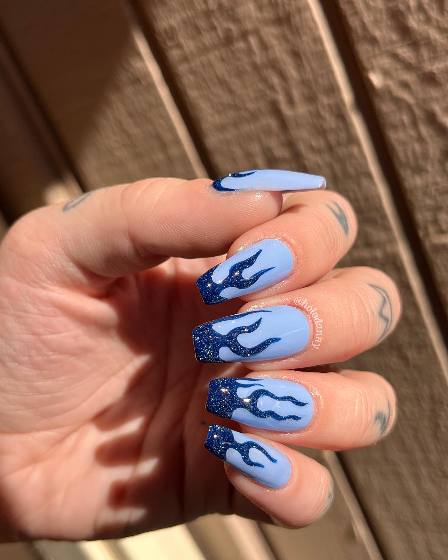 Blue is a color of the ocean and the sky and this makes it a great color to wear on your nails. To feel the blue vibes to the fullest, let's apply a baby blue nail polish and get dark blue glittered flame nail art to shine.