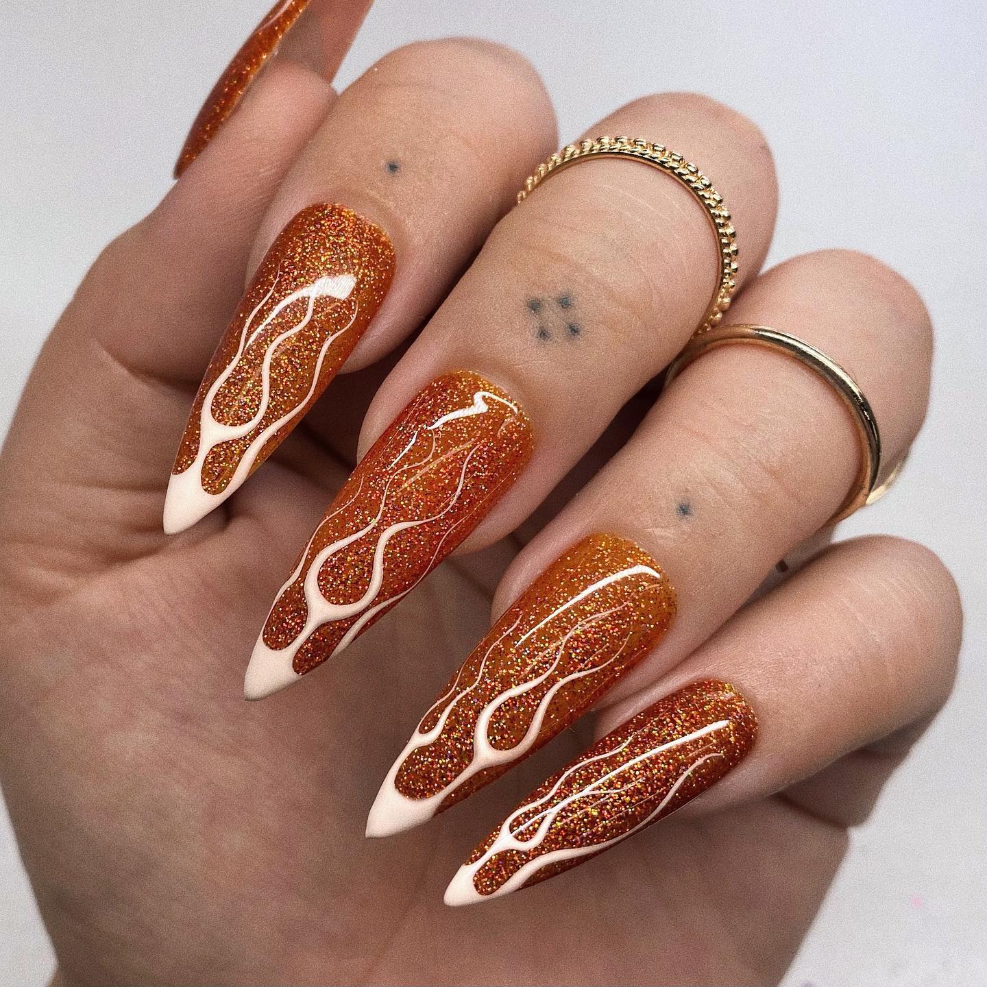 We can count these nails as Halloween nails because they are orange. Long stiletto mani is super daring with its white thin flames and it is sure to show your boldness.