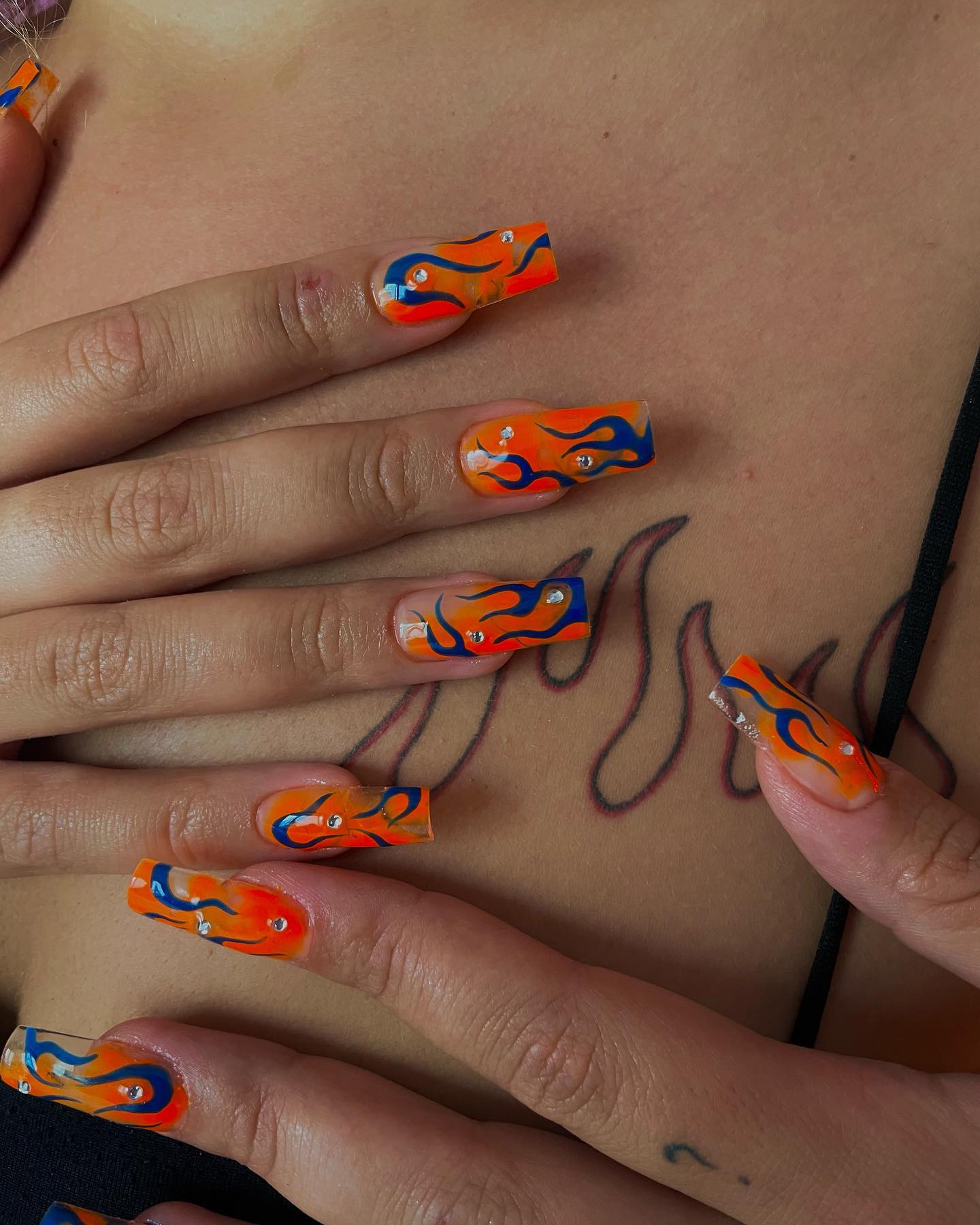 Orange and dark blue colors go well together because of their strong look. On your orange gel nails, dark blue flame-like swirls will cheer up your nails. Let's give it a shot.
