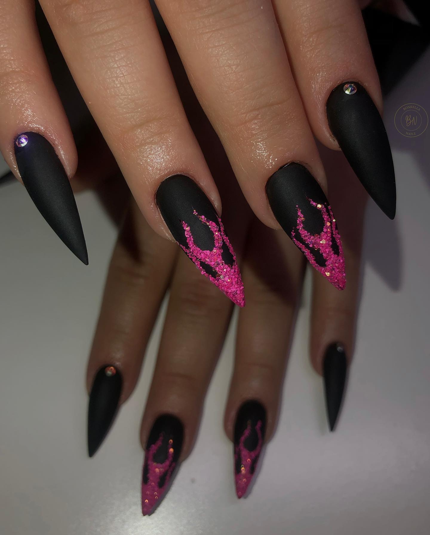 Matte black is one of those nail polish colors that is quite extraordinary to apply. If you want to try something new on your matte black nails, why not opt for glittered pink flames? Let's give it a shot.
