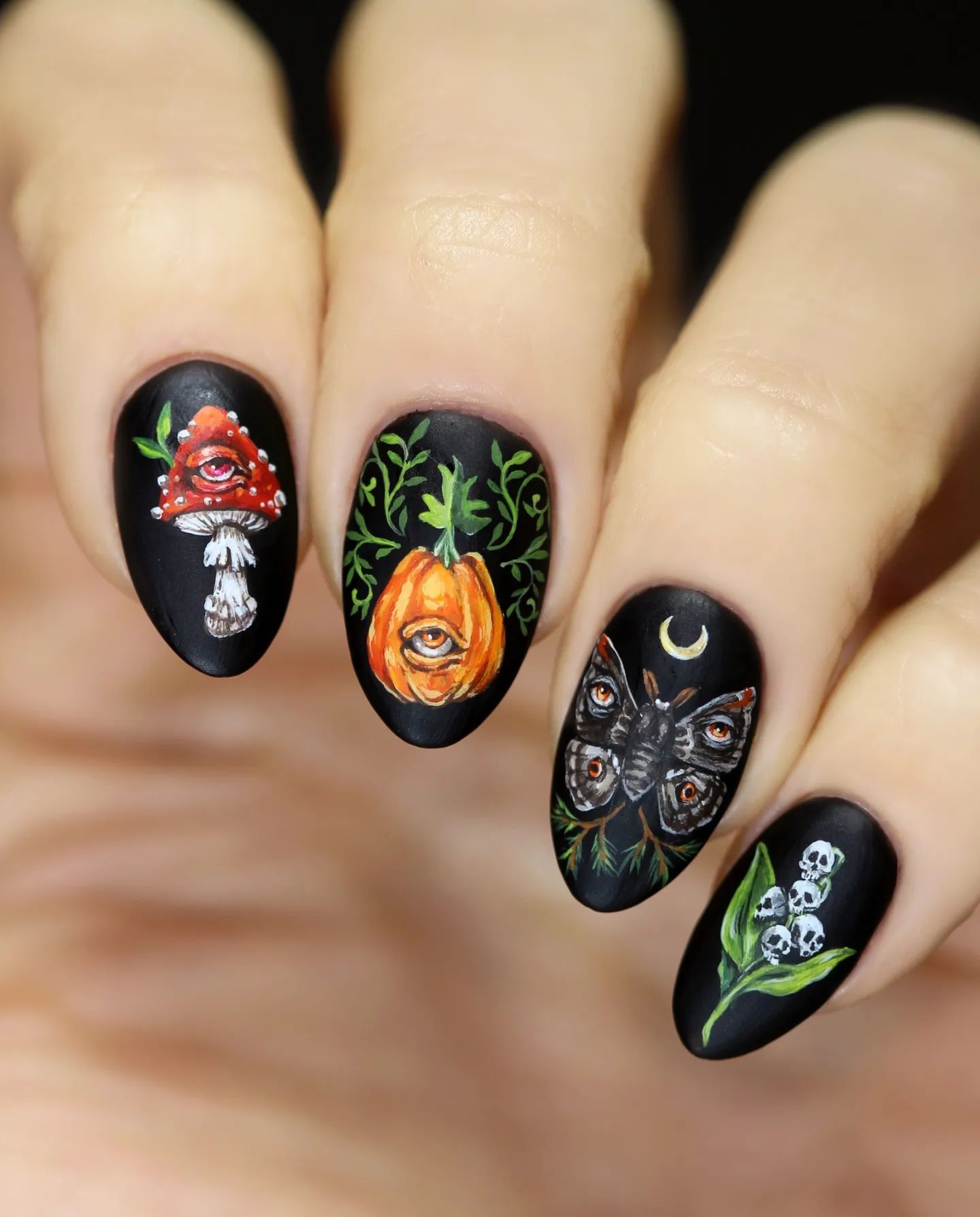 It is so hard not to be blown away! Just look at these incredible handprinted nails. The skulls, mushroom, pumpkin and butterfly details make this matte black nails totally amazing.