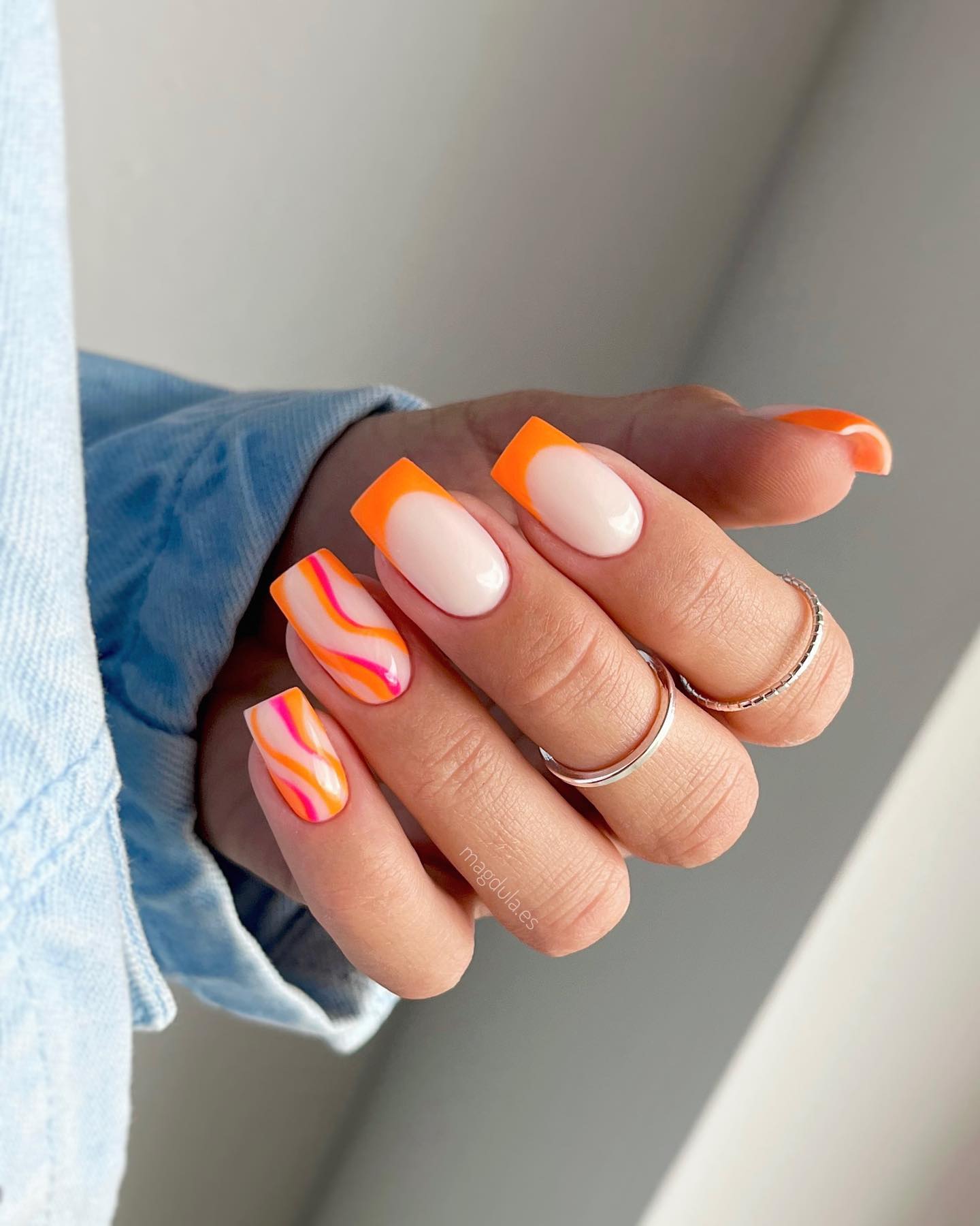 Those who are looking for something bold and fun, but also want to stay within the realm of classic style, orange French tips are great! When the sun is shining, your nails will shine, too. Plus, two accent nails with pink and orange swirls are so nice to go for.