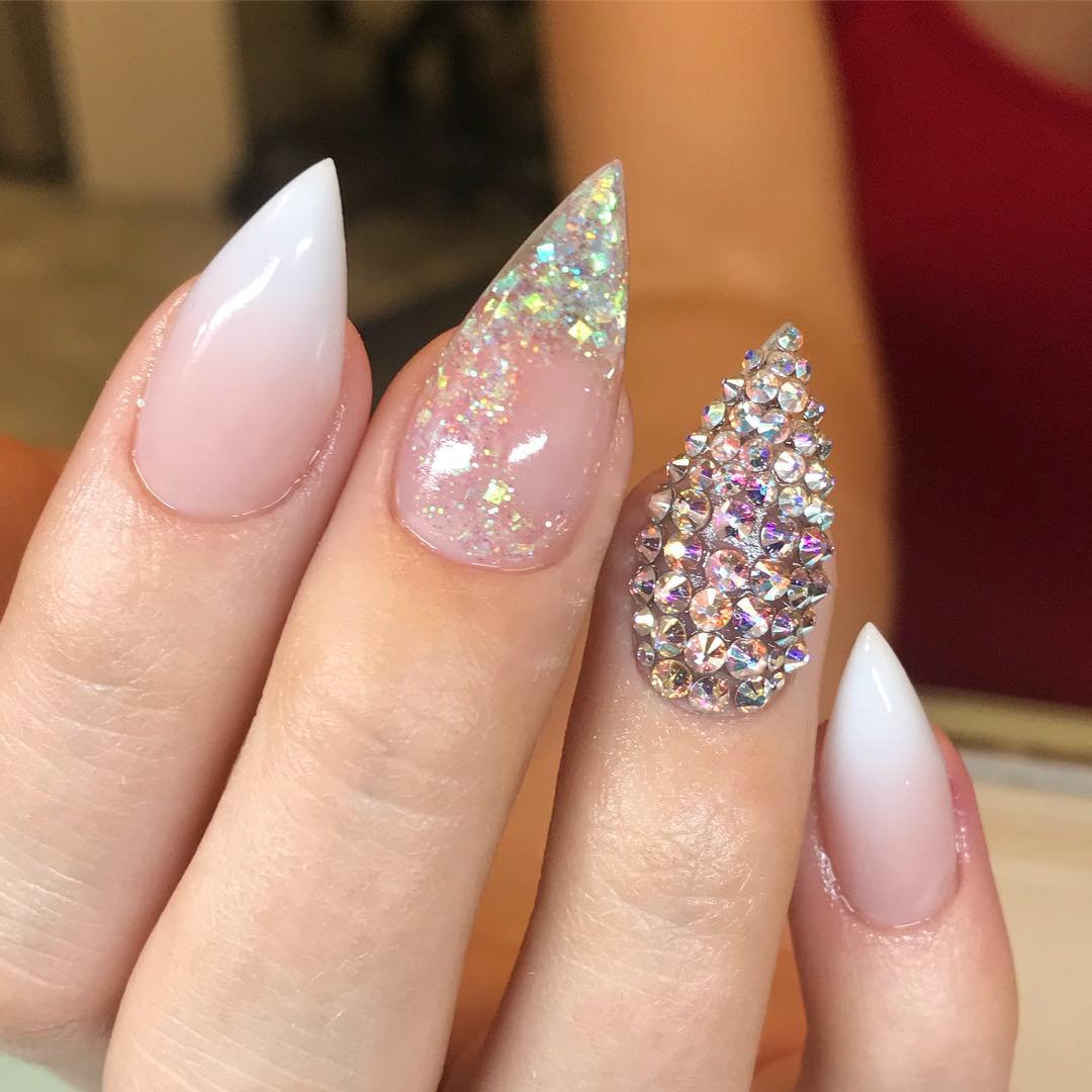 Want to have a sexy pink and white ombre nails? Then all you need to have is a stiletto manicure and add some details to it. If you're bold enough, covering your ring nail with shiny stones all over the place is a great idea to be unique. Let's go for it.